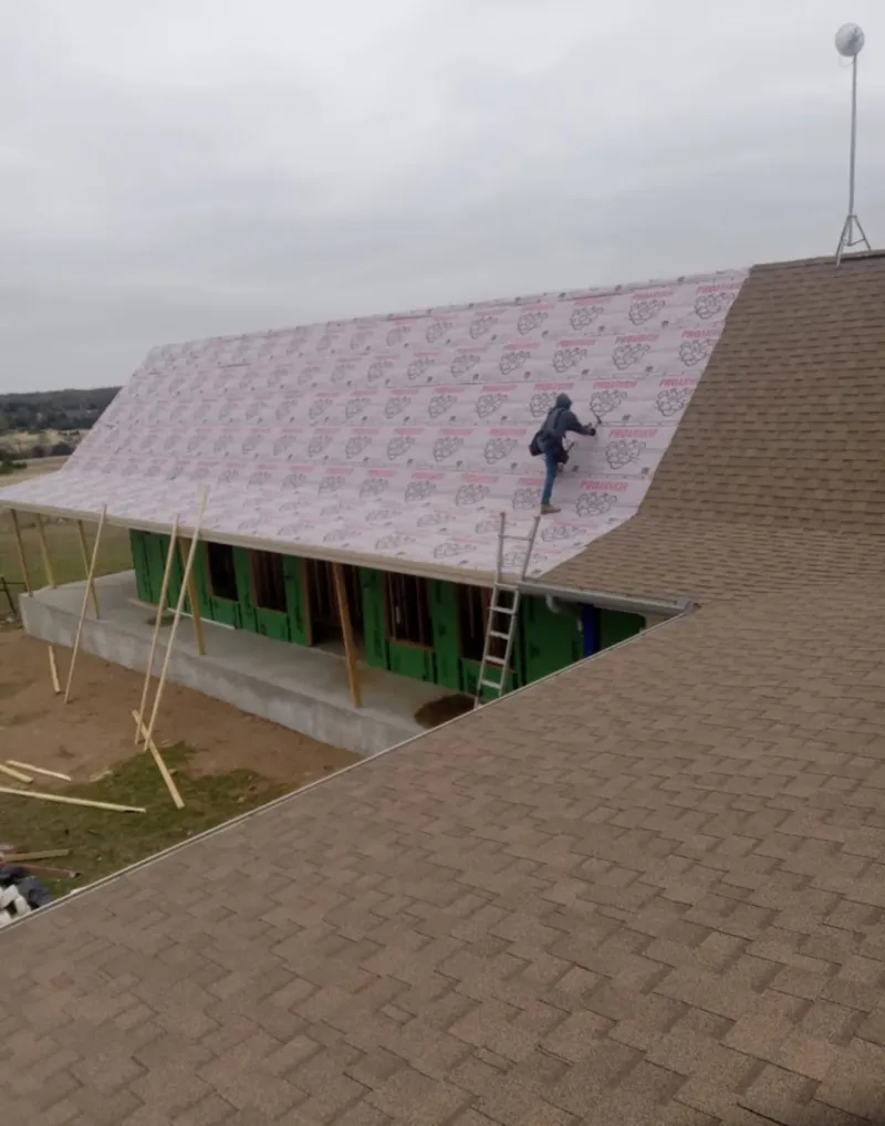 Worker preparing underlayment for a metal roof installation in Valinda